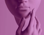 Abstract close-up of a sculptural face in purple tones, with a hand touching the chin. A conceptual image evoking perception and the ways we observe and interpret reality.