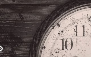 Primo piano di un orologio antico parzialmente visibile, con il quadrante segnato dal tempo. L’immagine suggerisce l’idea di tempo sottratto e disuguaglianze temporali.