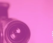 Close-up of a film camera lens in magenta tones, representing a way of observing reality through a different perspective.